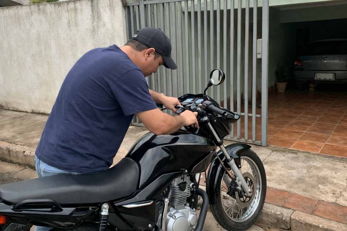 homem tentando ligar moto parada em frente &agrave; garagem